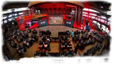 The interior of a red-lit circular hall lined with consoles and screens.